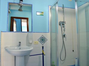 A bathroom with a white sink, a mirror, a shower enclosure, and a blue towel rack. - Room-suite Rosa - B&b S - Elia (Caltanissetta)