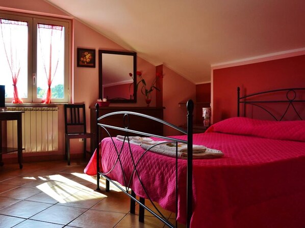 A bedroom with a bed, a desk, and a window with curtains. - Room-suite Rosa - B&b S - Elia (Caltanissetta)