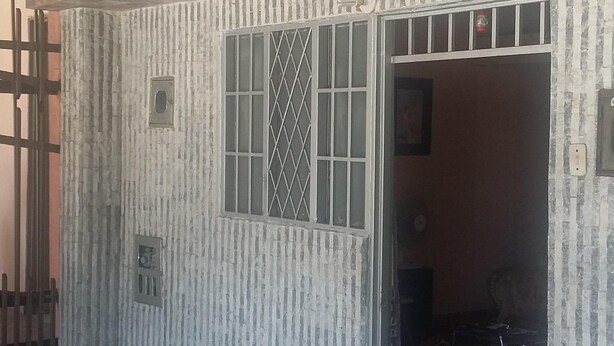 A building with a checkered facade, a large window with bars, and a door leading inside. - The Ancestral Magic of Huila for the Whole World (Neiva)