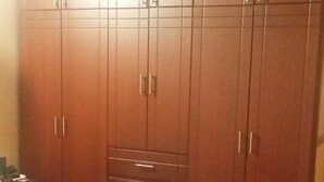 A bedroom with a large wardrobe, a bed with a patterned bedspread, and a tiled floor. - The Ancestral Magic of Huila for the Whole World (Neiva)