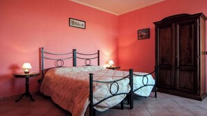 Ein Schlafzimmer mit einem Bett, zwei Nachttischen mit Lampen, einem Kleiderschrank und zwei gerahmten Bildern an der Wand.