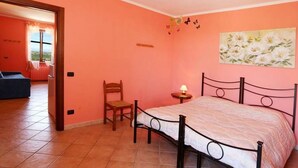 Ein Schlafzimmer mit Bett, Stuhl, Nachttisch und einem Bild an der Wand.