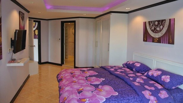 Un dormitorio con una cama, un televisor y una puerta que da a un baño.