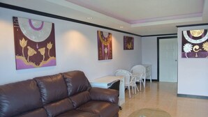 Una sala moderna con un sofá de cuero marrón, una mesa de centro de vidrio y un comedor con sillas blancas y una mesa.