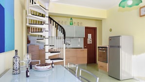 Une cuisine moderne avec un escalier en colimaçon, une table à manger avec des chaises et un réfrigérateur.