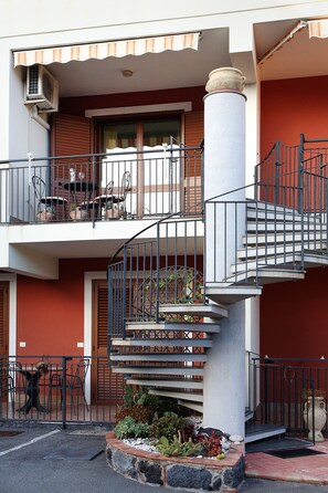 Stunning multi-story building with a central column and spiral staircase, featuring balconies, windows, and a charming garden.