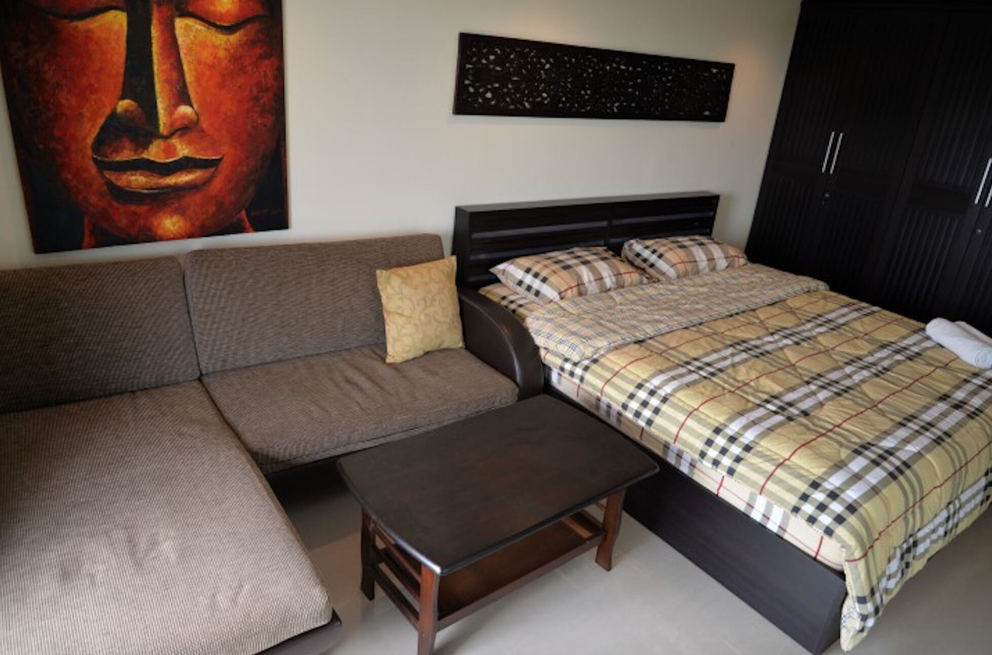 A bedroom with a bed, a sofa, a small table, and a painting on the wall.