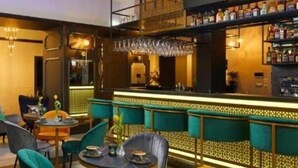 A bar area with a high counter, bar stools, and a seating area with round tables and chairs. - Hotel Estera (Kraków)