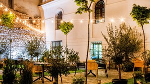 An outdoor patio area with string lights, potted plants, and outdoor furniture. - Hotel Estera (Kraków)
