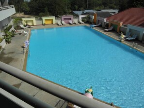 A swimming pool with lounge chairs and a small building in the background.
