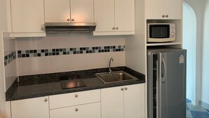 A kitchen with white cabinets, a stainless steel sink, a microwave, and a refrigerator. - Angket Hip Residence in Jomtien Angket Floor 15 Room (Pattaya)