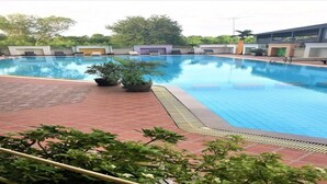 A swimming pool with a tiled deck, potted plants, and a building in the background. - Angket Hip Residence in Jomtien Angket Floor 15 Room (Pattaya)