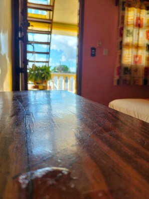 A wooden table with a view of a balcony and a plant. - Room-cancun Guest House 1 (Cancun)
