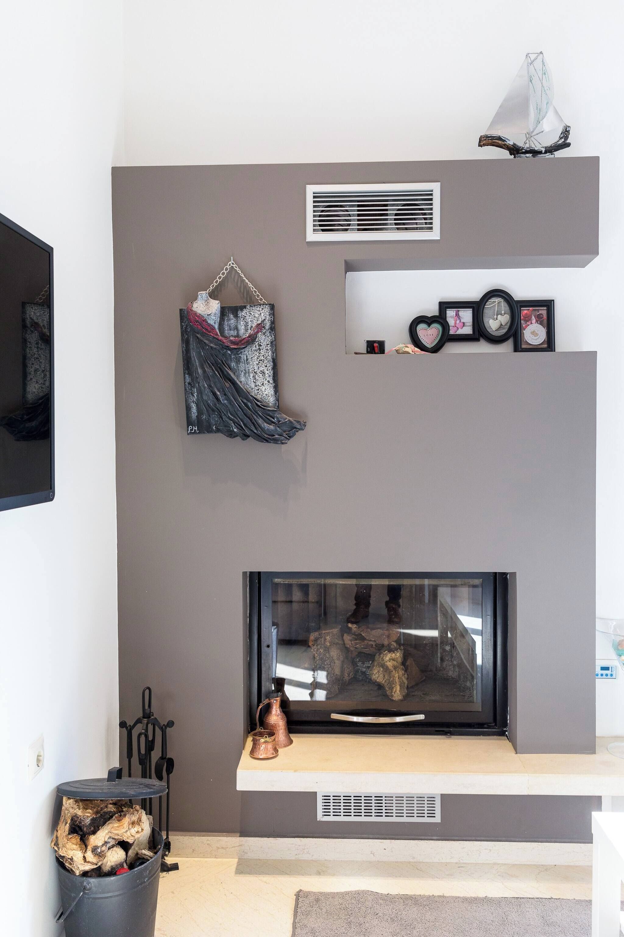 Un salón moderno con chimenea, una obra de arte colgada en la pared y un televisor.