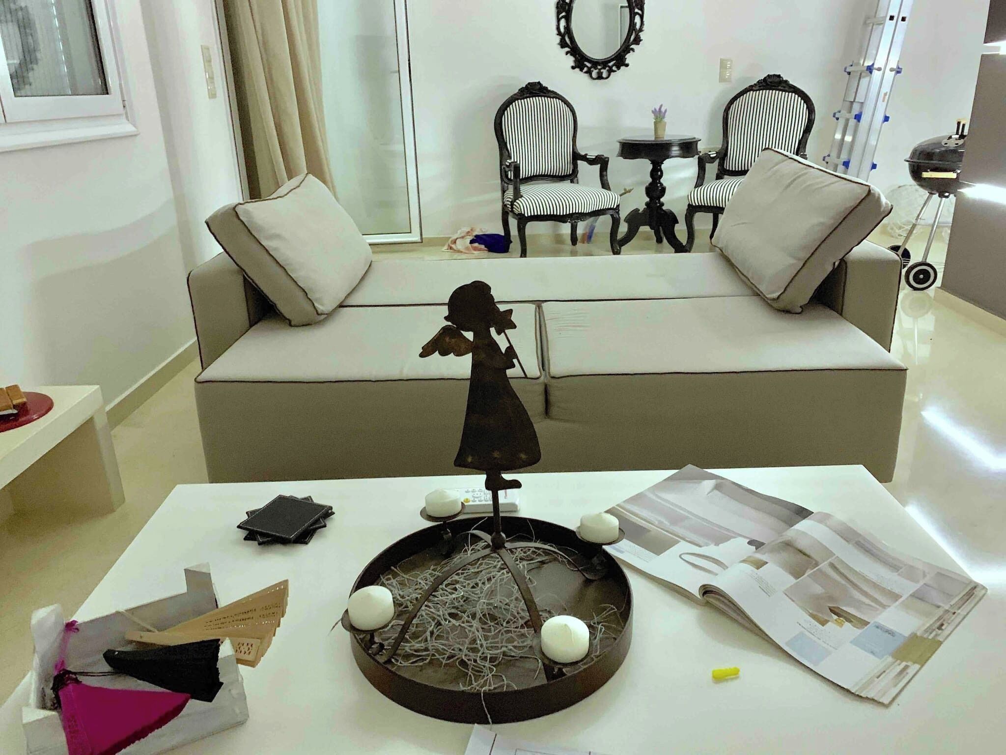 A living room with a sofa, two armchairs, a small table, and a decorative sculpture.