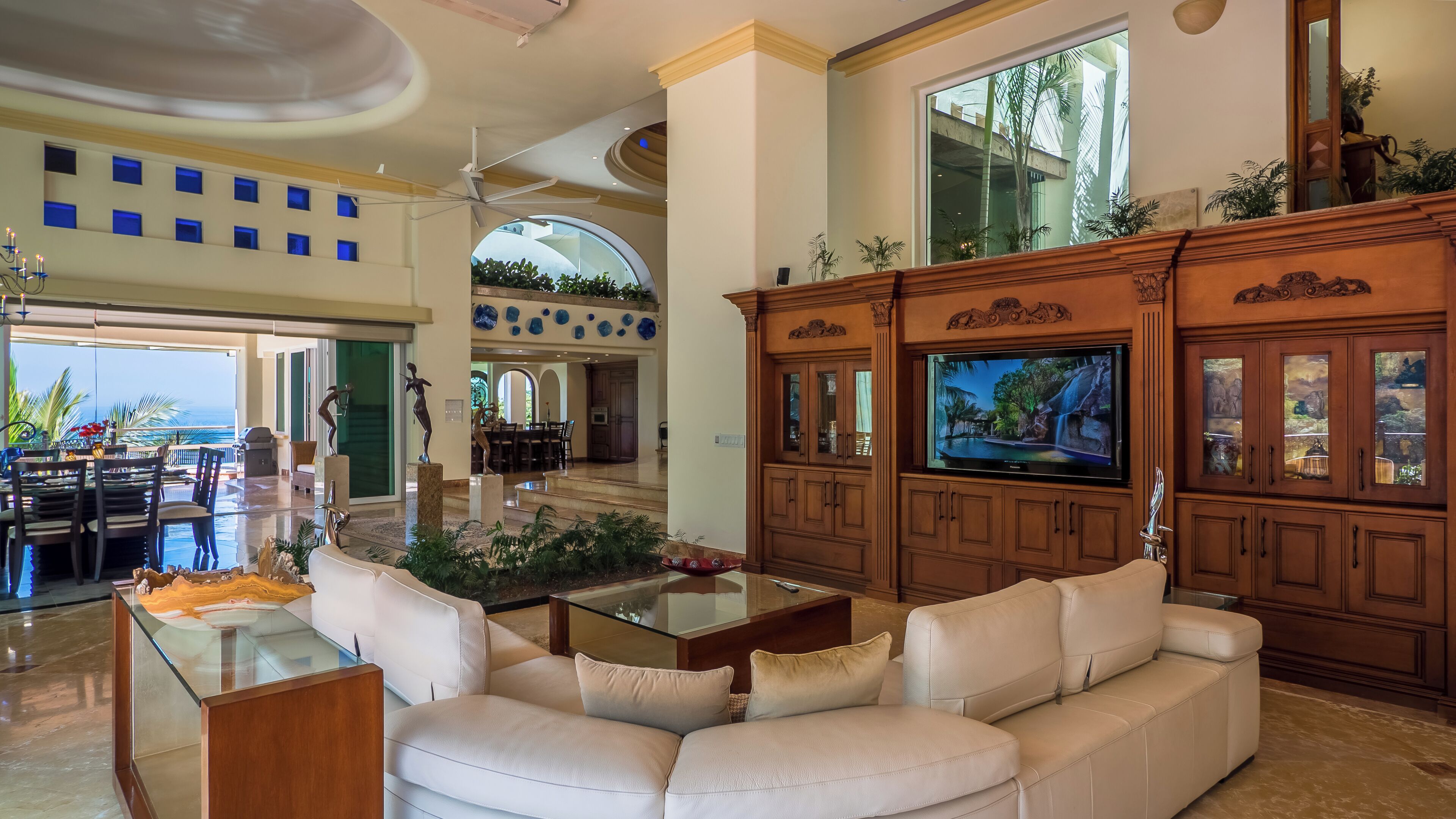 A spacious living area with a large TV, a white sofa, and a glass coffee table.