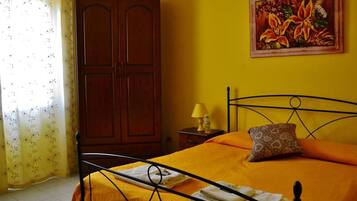 A room with a bed, a nightstand, a lamp, a painting, and a wardrobe.