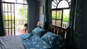 Une chambre à coucher avec un lit, une table de chevet, une lampe et une fenêtre avec des rideaux.