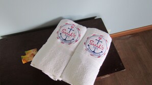 Deux serviettes blanches, ornées d’un logo et d’une inscription, sont posées sur une table en bois foncé.