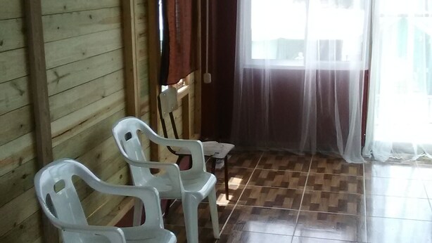 Ein Zimmer mit Holzwänden, gefliestem Boden und zwei weißen Plastikstühlen.