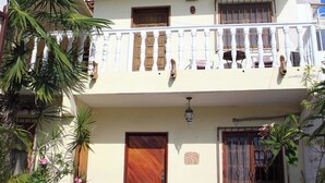 Un bâtiment à deux étages doté d’un balcon, d’une porte en bois et de plantes en pot.
