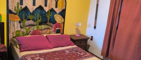 Un dormitorio con cama, mesita de noche, aire acondicionado instalado en la pared y cortina.