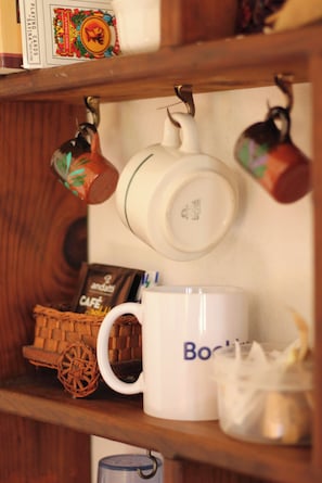 A shelf with a white mug, a coffee maker, and a basket. - Room-cancun Guest House 2 (Cancun)