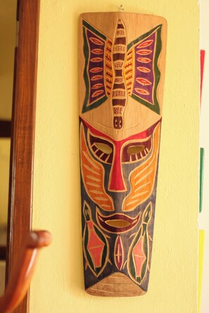 A wooden mask with geometric patterns and a carved handle, mounted on a wall. - Room-cancun Guest House 2 (Cancun)