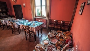 A dining area with multiple tables set with checkered tablecloths, wooden chairs, and a variety of food items. - Room-agriturismo Al Brich Double Room fo (Albaretto della Torre)