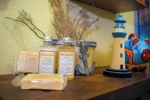 Une étagère avec des bouteilles de shampoing biologique, un savon et une décoration représentant un phare.