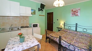 A compact room with a bed, a small table, a microwave, and a sink.