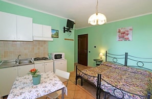 A compact room with a bed, a small table, a microwave, and a sink.