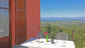A balcony with a table set for two, a bottle of wine, and a vase with a flower. - Agriturismo Al Brich Studio Apartment Margherita (Albaretto della Torre)