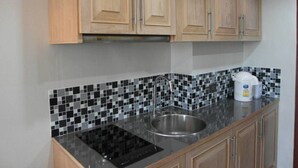 Una cocina con armarios de madera, salpicadero de baldosas blanco y negro, un lavamanos de acero inoxidable y una cafetera.