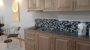 Una cocina con armarios de madera, salpicadero de baldosas blanco y negro, un lavabo de acero inoxidable y una cafetera.