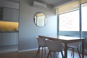 Een moderne keuken met grijze kastjes, een houten eettafel en vier witte stoelen.