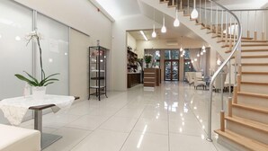 A spacious, modern interior with a polished tiled floor, a wooden staircase, and a glass door leading to another room. - Room in Guest Room - Valensija - Standard Twin Room (Jurmala)