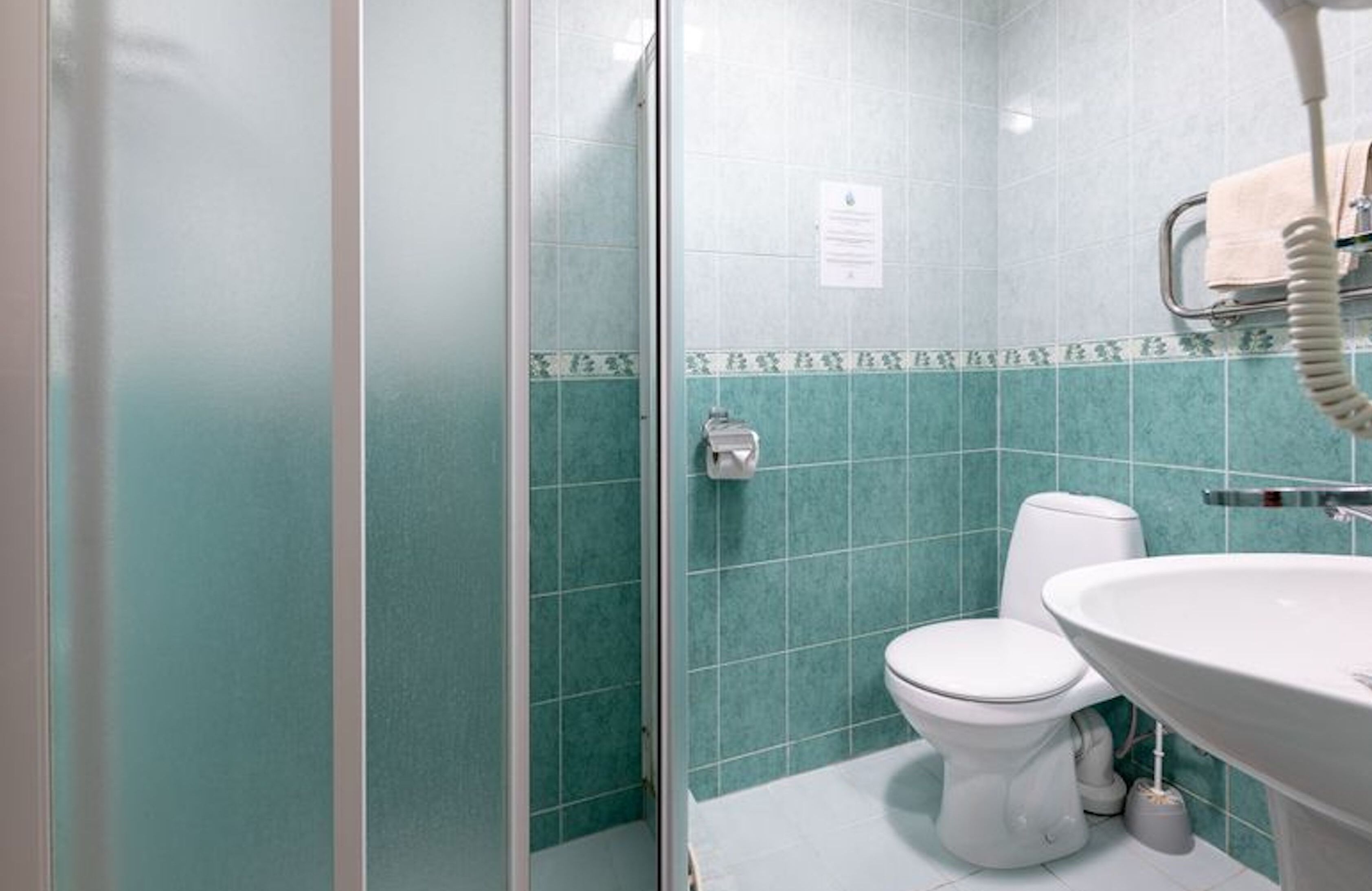A bathroom with a glass shower enclosure, a toilet, and a sink.