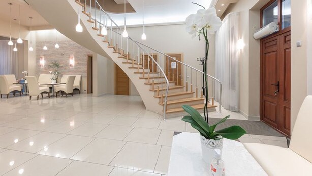 A spacious living area with a staircase, a dining table with chairs, and a potted orchid. - Room in Guest Room - Valensija - Standard Twin Room (Jurmala)