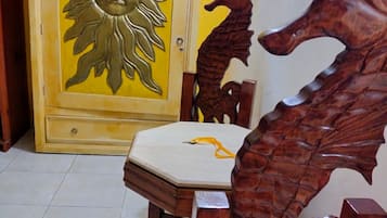 A wooden chair with a carved dragon backrest and a sun motif on a door.