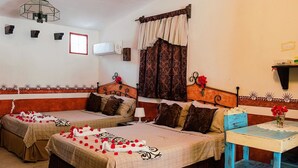 Una habitación con dos camas, una mesa, aire acondicionado en la pared y una ventana con cortinas.