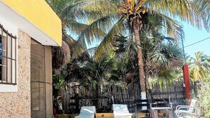 A building with a yellow facade, a window with bars, and a thatched roof. - Room-antigua Lodge, Away From the Crowds (El Cuyo)