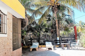 A building with a yellow facade, a window with bars, and a thatched roof. - Room-antigua Lodge, Away From the Crowds (El Cuyo)
