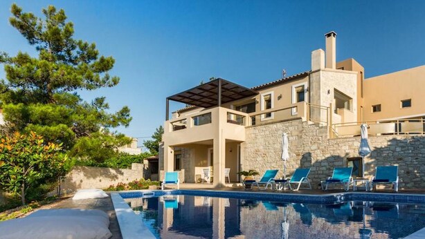 A modern villa with a swimming pool, outdoor seating, and a stone wall. - Palladio Villa Roussospiti (Rethymno)