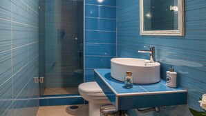 A bathroom with blue tiled walls, a white sink, a mirror, and a toilet. - Palladio Villa Roussospiti (Rethymno)