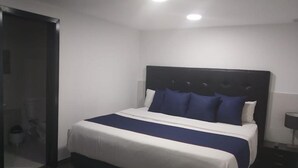A bedroom with a bed, a nightstand, and a door. - Hotel American Visa Bogota (Bogotá)