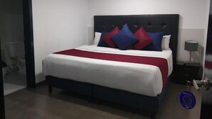 A hotel room with a bed, a nightstand, and a door. - Hotel American Visa Bogota (Bogotá)