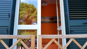 Quarto com uma janela grande, deck de madeira e parede laranja.