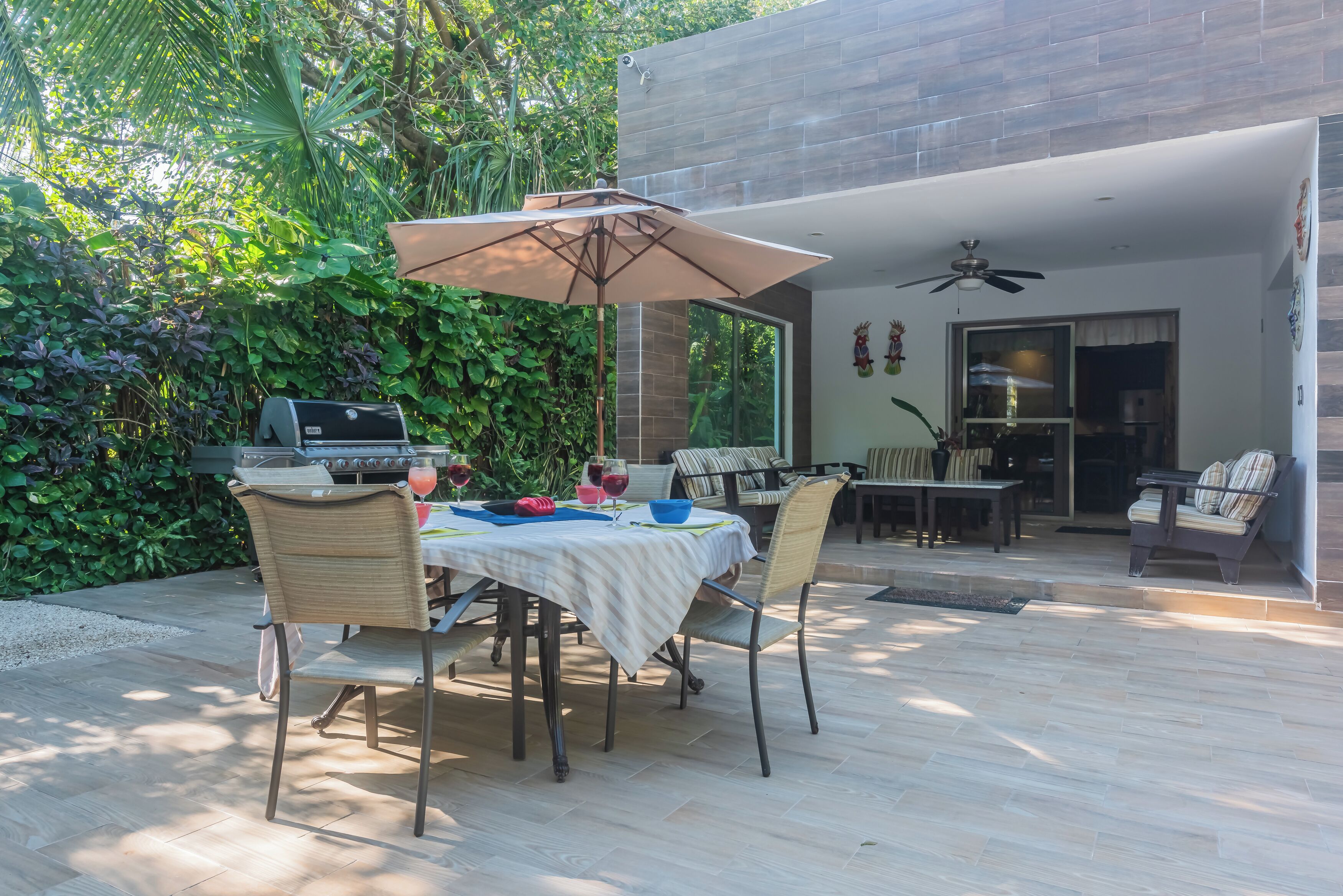 Un espace extérieur aménagé pour les repas, avec une table et des chaises, un barbecue et un ventilateur de plafond.