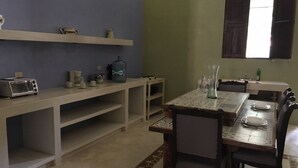 Una cocina con una mesa de comedor, sillas, un tostador y un dispensador de agua.
